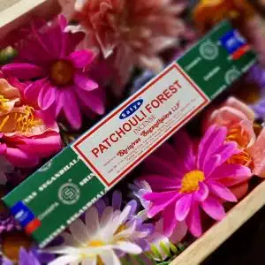 Satya Patchouli Forest 15g Incense Sticks box in wooden box surrounded by flowers